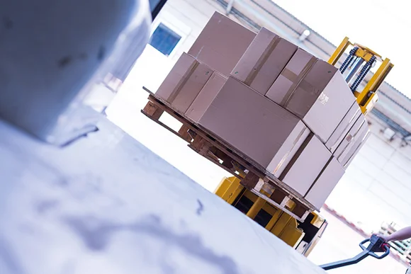 Gabelhubwagen hebt Palette mit Kartons an